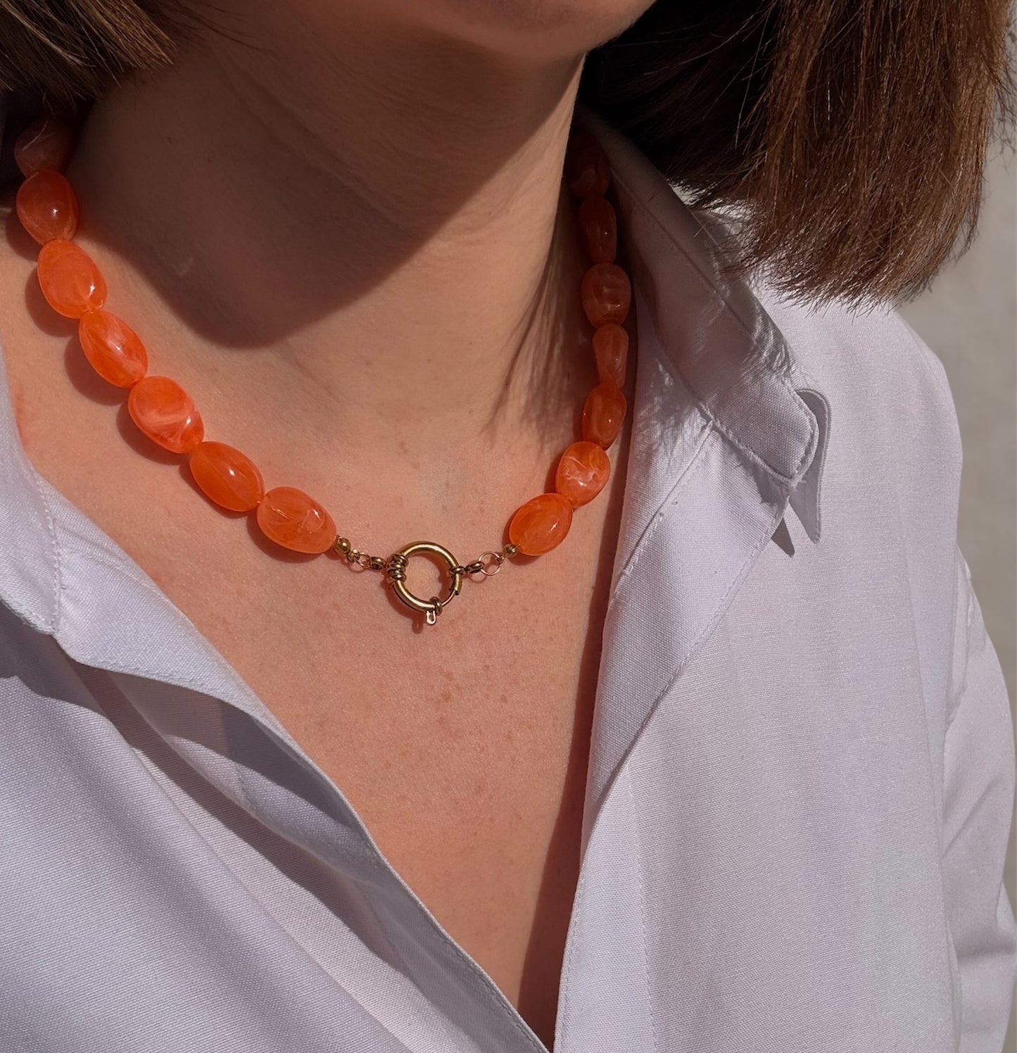 Collier Rivage orange porté avec fermoir doré visible à l'avant
