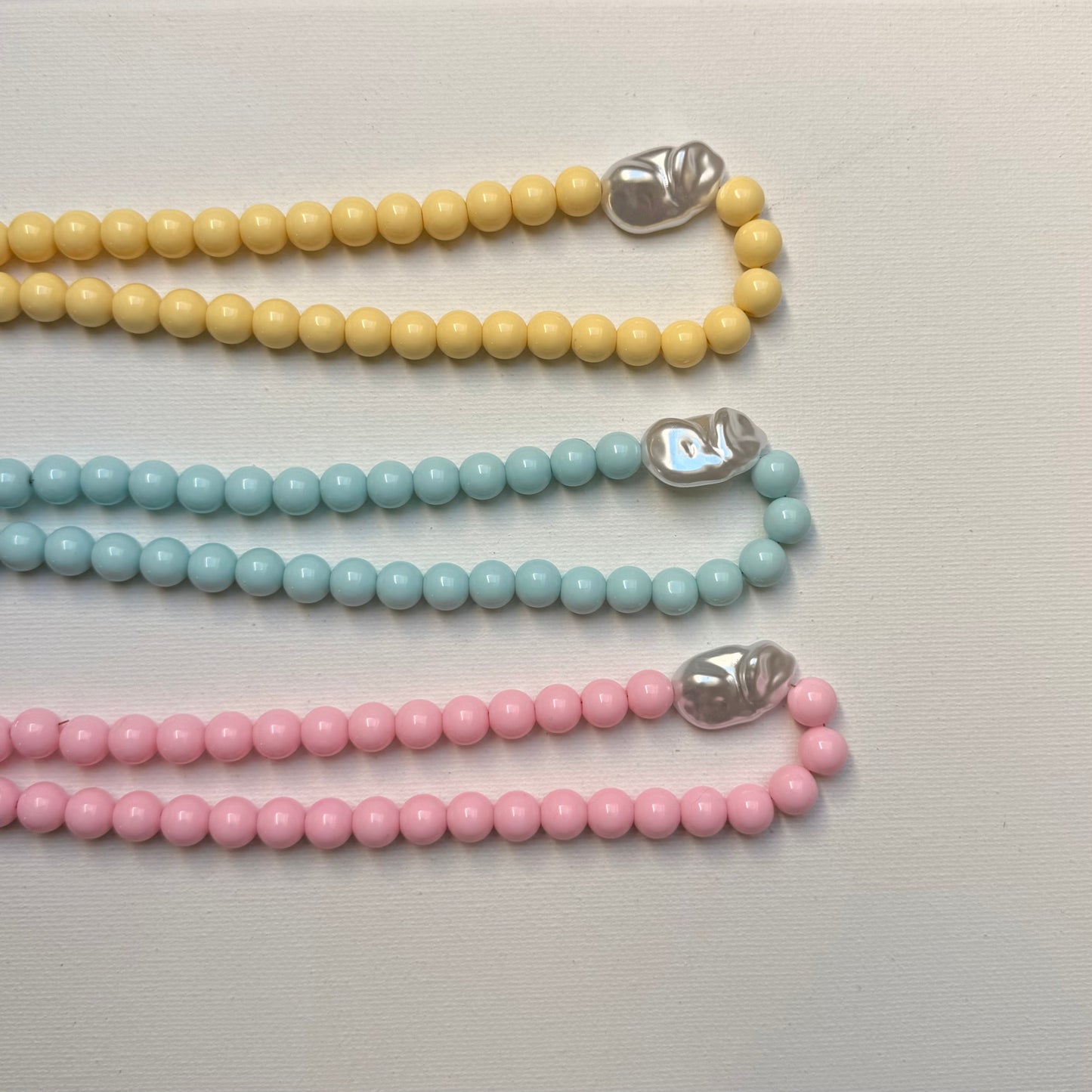 Collier Santorin rose, bleu et jaune pastel vue de dessus sur fond blanc