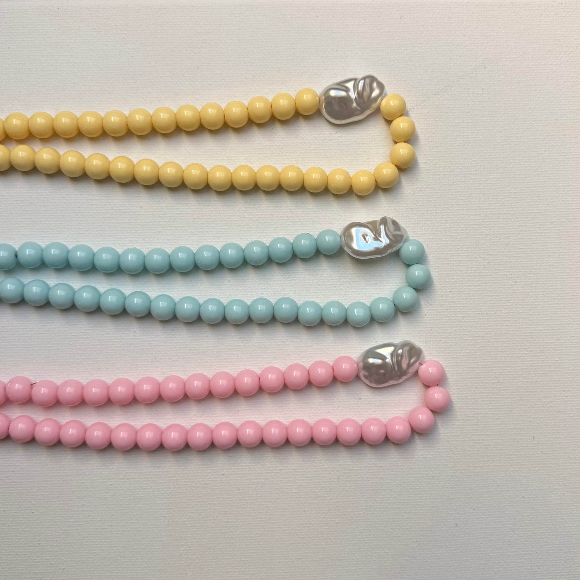 Collier Santorin rose, bleu et jaune pastel vue de dessus sur fond blanc